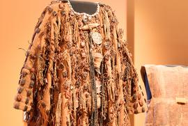 Close-up of an ancient hunter's coat embellished with beads, mirrors and animal teeth.  